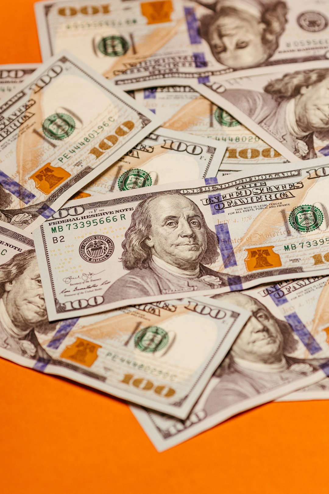a-pile-of-twenty-dollar-bills-sitting-on-top-of-an-orange-table-cvk49q7tpfu