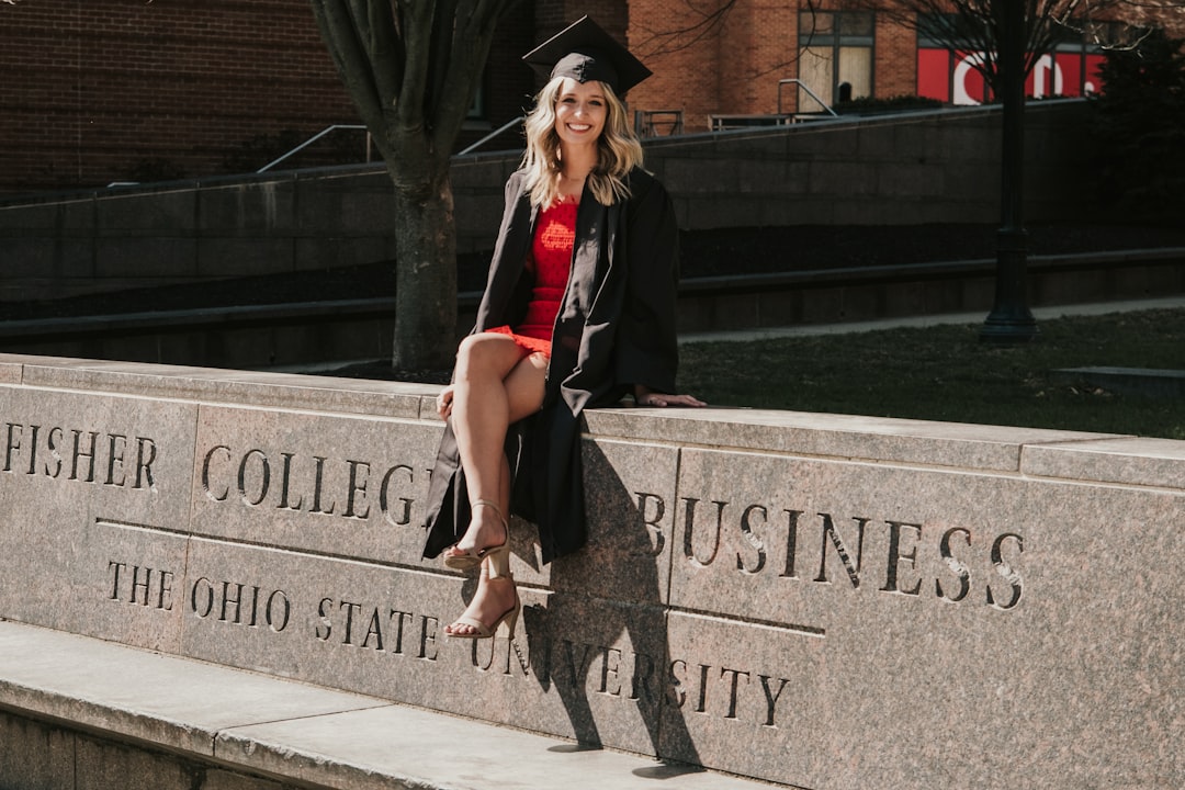 a-woman-in-a-graduation-gown-sitting-on-a-stone-wall-obmap57w53e